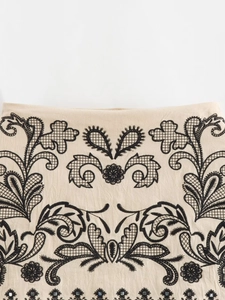 Detail of beige embroidery crop top with black floral patterns and beaded accents