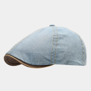Detail of light blue washed denim newsboy cap with brown leather trim and stitching