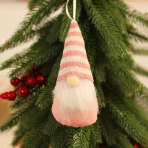 Close-up of a pink gnome ornament with a knitted hat hanging on a Christmas tree branch
