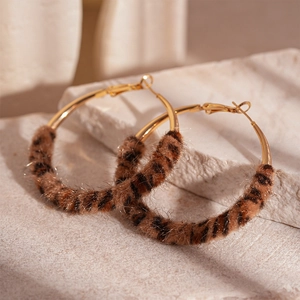 Detailed close-up of golden hoop earrings featuring leopard print plush texture for autumn