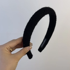 Detail of plush black headband featuring a handmade label and thick sponge design