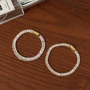 Detail of gold-plated bangle with baguette-cut zircons and secure clasp closure