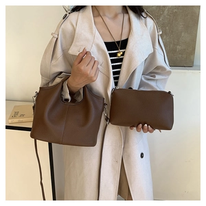 Close-up of brown litchi pattern bucket bag and matching pouch on beige coat