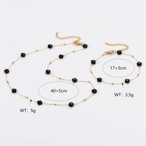 Gold chain necklace and bracelet set with black crystal beads on white background
