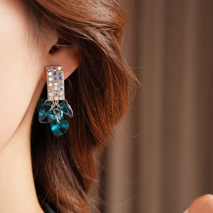 Detailed close-up of heart-shaped blue crystal drop earrings with sparkling rhinestones