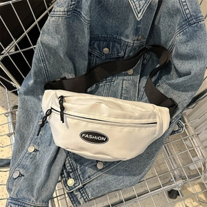Dettaglio borsa a tracolla intrecciata bianca con testo FASHION su una giacca di jeans