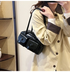 Detail of black glossy leather shoulder bag with vintage dual pockets and large buckles