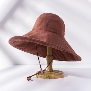 Detail of a brown wide-brim sun hat on a wooden stand with elegant natural light shadows