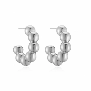 Detailed view of silver C-shaped earrings with polished bead texture on white background