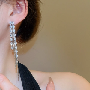 Close-up of elegant silver tassel earrings with sparkling crystals worn by a model