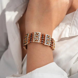 Detail of bohemian multilayer beaded bracelet with vintage gold metal and orange rhinestones