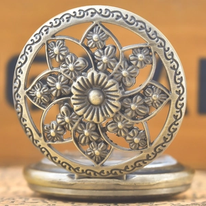 Detailed view of antique bronze pocket watch with intricate floral filigree carving