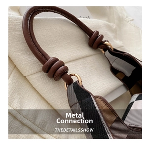 Detail des Ledergriffs und des goldenen Metallrings an der karierten Mondsichel-Tasche