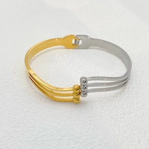 Detail view of a two-tone stainless steel bangle featuring a gold and silver wavy design