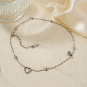 Detail eines silbernen Herz-Armbands aus Edelstahl mit funkelnden Strass-Anhängern