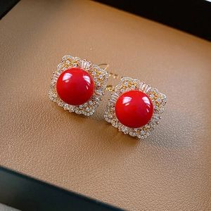 Macro shot of vintage gold square stud earrings with red gems and zircon stones