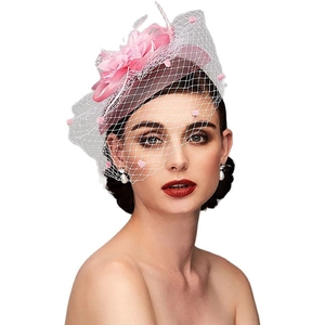 Detailed view of a pink floral fascinator with feathers and polka dot mesh veil