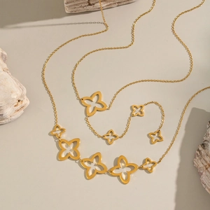 Elegant gold clover necklace with white mother of pearl inlays on natural stone background
