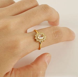 Detail of 18K gold plated sunflower ring with oval zircon on hand in neutral background