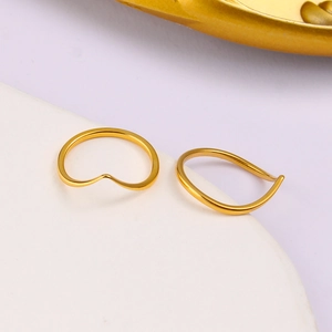 Close-up of two stackable V-shaped gold-plated stainless steel rings on a display stand