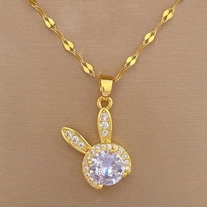 Close-up of golden bunny head pendant necklace with sparkling crystal inlay on texture