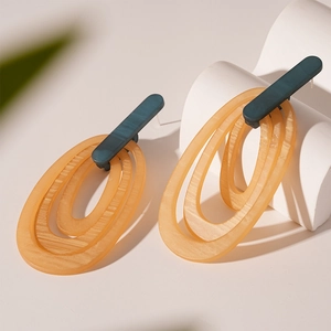 Detailed close-up of amber resin striped earrings on white minimalist stone pedestal