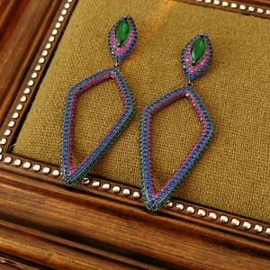 Detailed macro of vintage flower earrings with green stones on green velvet background