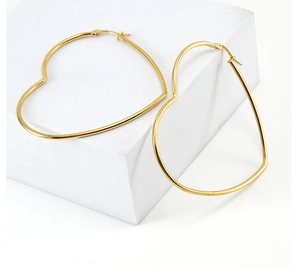 Detail of minimalist gold heart-shaped hoop earrings on white geometric prop