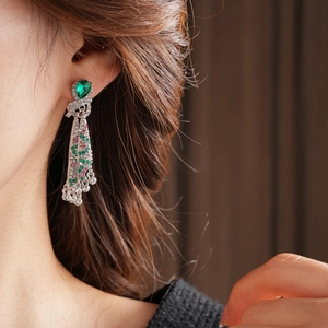 Detail of vintage silver fringe earrings with green teardrop stones and colorful crystals