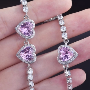 Detailed macro view of pink heart-shaped zirconia tennis bracelet with silver plating