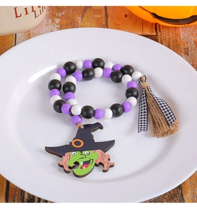 Dettaglio ghirlanda di perle di legno per Halloween con strega e fiocco a scacchi