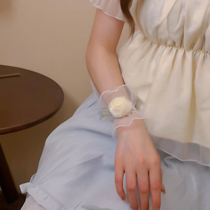 Bracelet en dentelle avec rose en satin crème porté par un modèle dans un cadre élégant