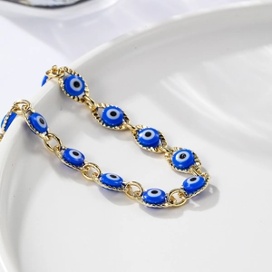 Bohemian gold evil eye bracelet with blue eye charms on white ceramic background