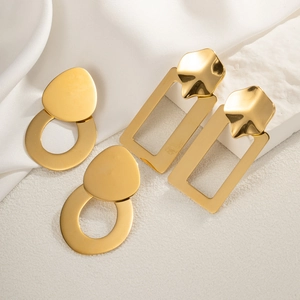 Detail of geometric gold earrings in oval and rectangular hollow shapes on white fabric