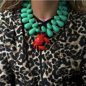 Ocean-inspired turquoise beaded necklace with a vibrant red crab pendant on a model