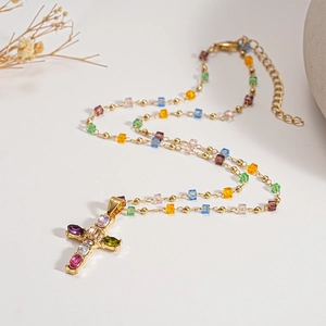 Golden necklace with multi-colored square beads and a jeweled cross pendant on white