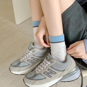 Baskets rétro 990v5 grises en daim et mesh portées, montrant le profil latéral du pied