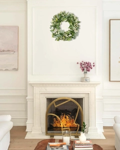 Detail of faux eucalyptus wreath with white berries hanging over a fireplace for home decor