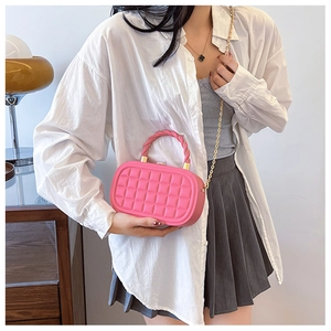Detail of pink woven texture box bag with gold twist handle and chain strap on model
