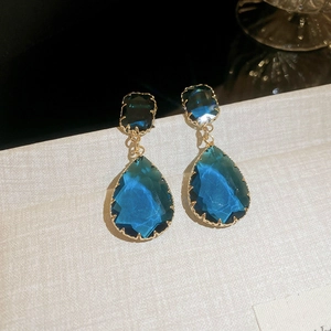 Vue macro détaillée de boucles d'oreilles dorées avec pierres bleues en forme de goutte