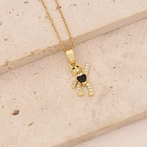Detail of golden teddy bear necklace featuring black heart stone and zircon accents