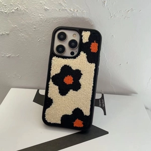 Close-up of floral plush embroidery on iPhone case with black, white, and orange texture