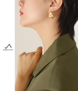 Gros plan de boucles d'oreilles irrégulières dorées et ensemble de bagues assorties