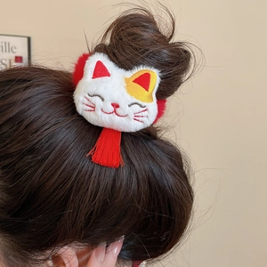 Detail of plush cat hair tie with red tassels on a messy bun hairstyle