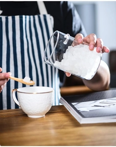 Action shot of glass storage jar with wooden lid and spoon scooping ice cubes
