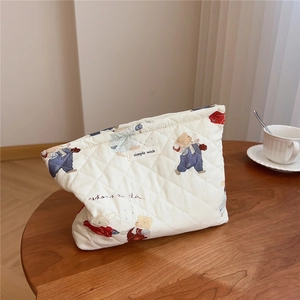 Detailed close-up of quilted cotton cosmetic bag with bear print and branded label