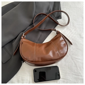 Top view of a brown glossy leather crescent bag showing size with a mobile phone