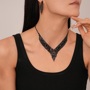 Close-up of black V-shaped fringe necklace and matching earrings on a model