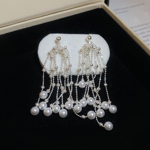Detailed view of silver zircon tassel earrings with white pearls on a black velvet box