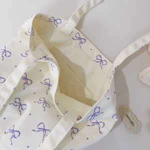 Close-up of internal pocket and purple bow floral print on beige canvas tote bag